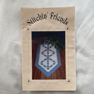 May include: A quilting pattern booklet titled "Stitch'n Friends" featuring a blue and yellow table runner with a diamond pattern. The pattern is titled "Quilted Crossroads #991".