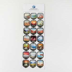 May include: A sheet of 25 National Park stickers featuring colorful illustrations of iconic landmarks and scenery from each park. The stickers are shaped like shields with black borders and white text. The parks featured include: Sequoia, Crater Lake, Arches, Badlands, Big Bend, Yosemite, Zion, Canyonlands, Glacier, Yellowstone, Grand Canyon, Rocky Mountain, Voyageurs, Olympic, Yosemite, Grand Teton, Denali, Death Valley, Everglades, Glacier Bay, and more.
