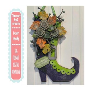 Puede incluir: Decoración de Halloween de madera con forma de bota de bruja, pintada de morado y verde, con un arreglo floral en la parte superior. La bota tiene una hebilla y el texto "A bad Witch would never wear shoes this FABULOUS!" está en una etiqueta. La imagen también incluye el texto "Timeout 4u2 create".