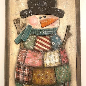 May include: Wooden sign featuring a snowman with the text "LET'S GET COZY". The snowman wears a black top hat, an orange carrot nose, and a blue scarf. The body is made of patchwork fabric in various colours and patterns.