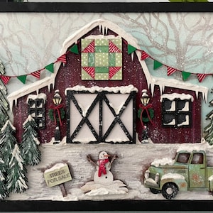 May include: A red barn with a green and red quilt block on the front, surrounded by snow-covered trees and a green pickup truck. The barn has a sign that reads "Trees for Sale".
