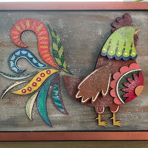 May include: A colorful wooden rooster with a patterned tail and the text "cock-a-doodle-doo cock-a-doodle-doo" on a brown wooden background.