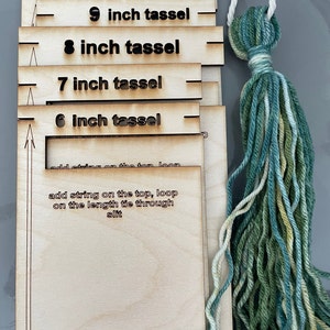 Puede incluir: Un fabricante de borlas de madera con instrucciones para hacer borlas de 6, 7, 8, 9 y 10 pulgadas de largo. Las instrucciones incluyen agregar cuerda en la parte superior, hacer un bucle con la cuerda de longitud a través de la ranura y cortar en la parte inferior. Se muestra una borla verde y amarilla a la derecha.