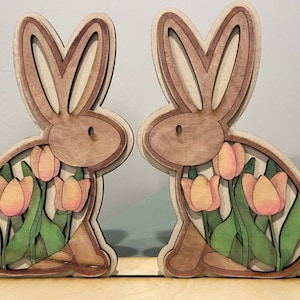 Coelhinhos e tulipas, arquivo svg do Glowforge. Contém dois coelhinhos e um suporte para colocar na sua mesa. Os coelhinhos podem ser pintados de várias maneiras diferentes.