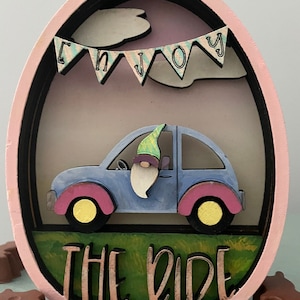 Enjoy the ride egg glowforge svg download file. This egg is made of layers to create a 3D effect of a gnome in a car.