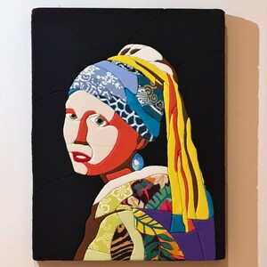 Può includere: Un'opera d'arte colorata e strutturata che raffigura una donna con un orecchino di perla, che ricorda il famoso dipinto. Il pezzo presenta uno sfondo nero e una vibrante gamma di colori, tra cui rosso, giallo, blu e verde.