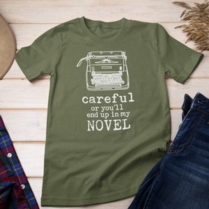 May include: A green t-shirt with a white typewriter graphic and the text "careful or you'll end up in my NOVEL".