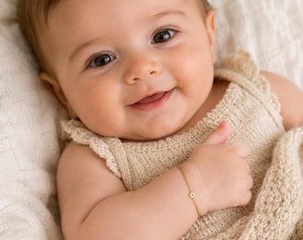 May include: A delicate gold chain bracelet featuring a small, six-pointed star charm. The bracelet is worn on a wrist, showcasing a thin, polished metal link design that secures with a clasp, highlighting the minimalist jewelry piece.