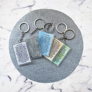 Pode incluir: Quatro chaveiros coloridos com texto em hebraico. Os chaveiros est&atilde;o presos a argolas de chave prateadas. Os chaveiros est&atilde;o sobre um fundo cinza.