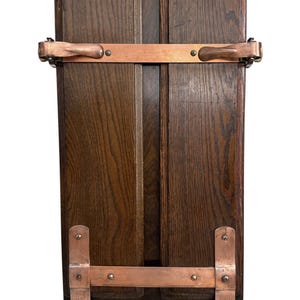 Könnte beinhalten: Ein Vintage-Holzstaffelei mit dunkelbraunem Finish. Es verfügt über kupferfarbene Metallakzente und Scharniere mit einem Etikett mit der Aufschrift "WALT'S WRIGHT". Die Staffelei ist so konzipiert, dass sie sich zur Aufbewahrung und zum Transport flach zusammenklappen lässt.