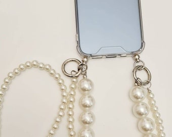 May include: A clear phone case with a pearl phone strap. The strap has two strands of pearls, one with larger pearls and one with smaller pearls.