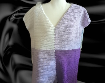 May include: A handmade crochet top in a patchwork design. The top features a V-neck and short sleeves. The color scheme includes white, light purple, medium purple, and dark purple squares. The top is displayed on a mannequin.
