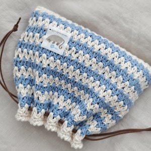 May include: A blue and white crocheted drawstring bag with a small tag that reads "Handmade with love".