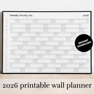 May include: A black framed 2026 wall calendar with a minimalist design. The calendar grid is light gray on a white background. The words "twenty twenty-six" and "2026" are at the top. A black circle with "INSTANT DOWNLOAD" is on the right.