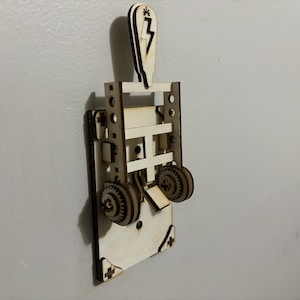 May include: A wooden light switch with a lightning bolt design on the top. The switch has a lever that moves up and down to turn the light on and off. The switch is made of light brown wood and has a white background.
