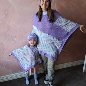 Peut inclure: Deux personnes portant des ponchos et des chapeaux assortis à rayures violettes et blanches. L'adulte porte un pantalon noir et des baskets montantes noires. L'enfant porte une robe rose et blanche.
