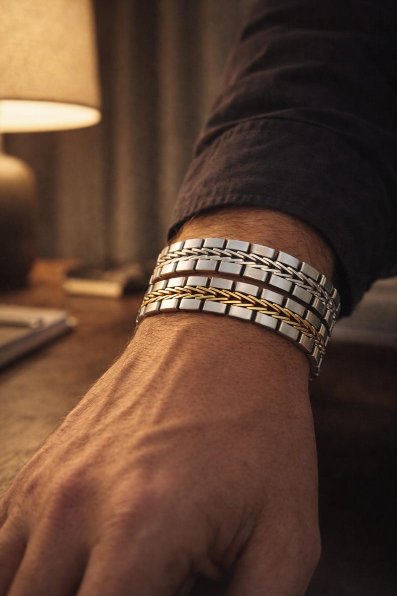 May include: A selection of silver and gold bracelets. The bracelets, made of rectangular links, are stacked on a wrist. The bracelets combine silver and gold tones, creating a stylish accessory. The wrist is visible.