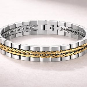 May include: A silver and gold-tone bracelet. The bracelet has a rectangular link design with a central band of interwoven gold-tone links. The clasp is silver-tone. The bracelet is a piece of jewellery.