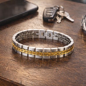 May include: A silver and gold bracelet with a woven gold centre section. The bracelet is on a wooden surface, with a watch, keys, and a smartphone in the background. The watch has a silver band and a dark face.