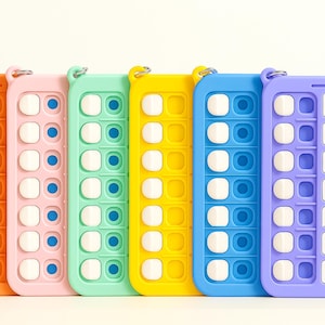 May include: Six colorful silicone fidget toys with different designs. Each toy has a series of buttons that can be pushed in and out. The toys are all in a row and are arranged from left to right in the following order: orange, pink, green, yellow, blue, and purple.