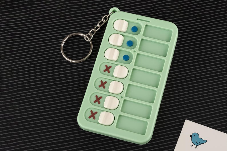 May include: A mint green pill organizer keychain with a silver key ring. The organizer has eight compartments, each with a white pill and a red X or a blue dot.