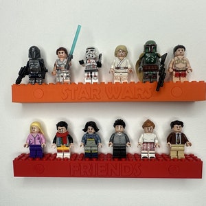 May include: Two red shelves with the words "STAR WARS" and "FRIENDS" printed on them. The top shelf has 8 Lego minifigures, including a Stormtrooper, Boba Fett, and a Mandalorian. The bottom shelf has 7 Lego minifigures, including a female character with pink hair and a male character with a brown shirt and a red scarf.