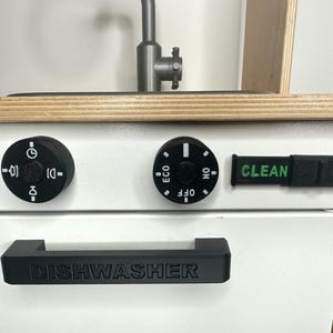 May include: A white toy dishwasher with a black handle and control knobs. The dishwasher has a "CLEAN" label and a knob that says "ECO, OFF, ON".