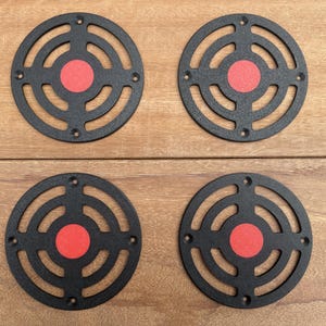 May include: Four black circular vent covers with a red centre circle. Each cover has concentric circles around the centre.