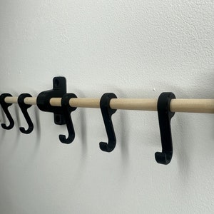 May include: Black metal wall-mounted coat rack with a wooden rod and five hooks.