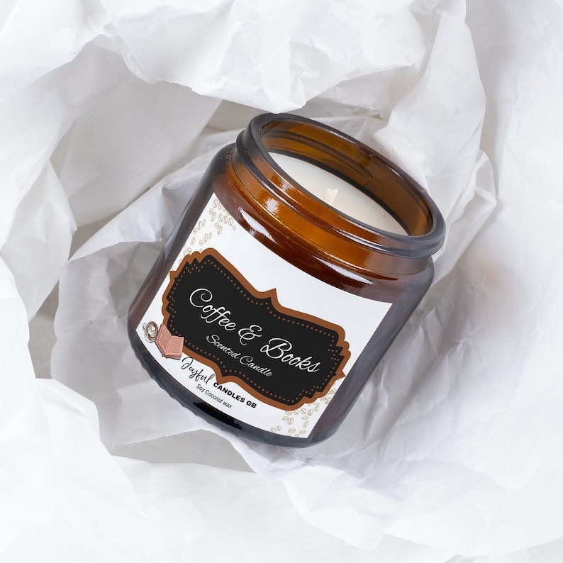 May include: A brown glass jar candle with a white label that reads "Coffee & Books." The candle has a white wax interior. The label features a coffee cup and book graphic. The candle is on a white, textured surface.