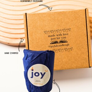 May include: A brown cardboard box with black text reading made with love just for you and @joyfulcandlesgb, accompanied by a blue tissue-wrapped item featuring a circular white label with the text joy ful.