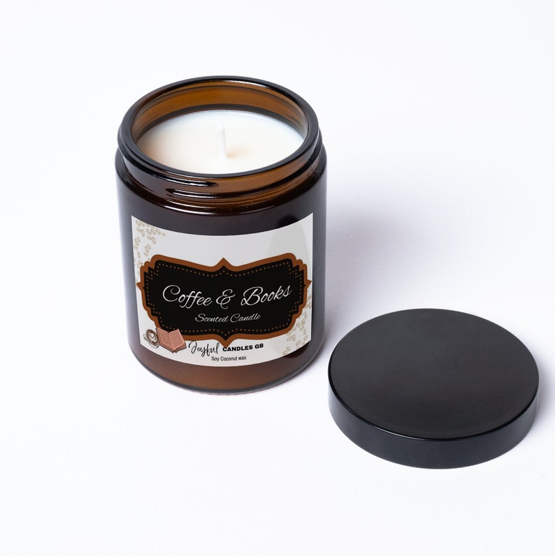 May include: A brown glass jar candle with a white wick and a black lid. The label reads "Coffee & Books Scented Candle" with a coffee cup and book illustration. The candle is made with soy coconut wax.