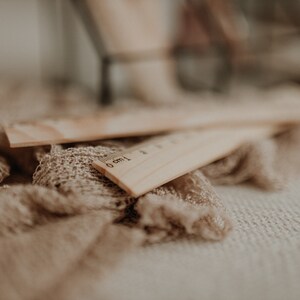 Puede incluir: Dos reglas de madera con un fondo de tela marr&oacute;n. La regla de arriba tiene los n&uacute;meros 0 cm y 1 cm impresos en ella.