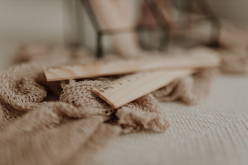 Puede incluir: Dos reglas de madera con un fondo de tela marr&oacute;n. La regla de arriba tiene los n&uacute;meros 0 cm y 1 cm impresos en ella.