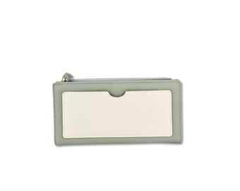 Può includere: Un portafoglio rettangolare di colore verde chiaro con una tasca centrale bianca. Il portafoglio ha una chiusura a zip ed è realizzato in un materiale strutturato. Il design è semplice e moderno.