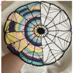 Peut inclure: Un tapis rond en crochet avec un motif rayé noir, blanc, rose, jaune et bleu sur une moitié et un motif de toile d'araignée blanche en crochet sur l'autre moitié.