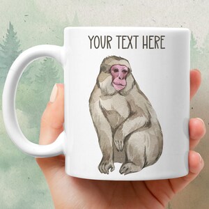 May include: White ceramic mug with a watercolor illustration of a Japanese macaque monkey. The text "YOUR TEXT HERE" is printed on the mug.