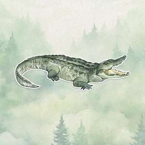 May include: A sticker featuring a detailed illustration of a green alligator with a textured, scaly back and a long, curved tail. The alligator is depicted in a side profile view with its mouth open, revealing sharp teeth and a light-coloured interior.