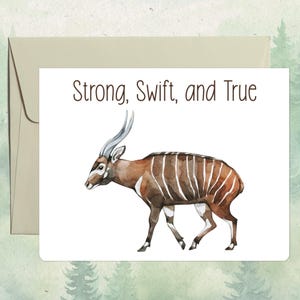 May include: A white greeting card featuring a watercolor illustration of a bongo antelope with reddish-brown fur and white vertical stripes. The text "Strong, Swift, and True" is printed in dark brown above the animal, accompanied by a light envelope.