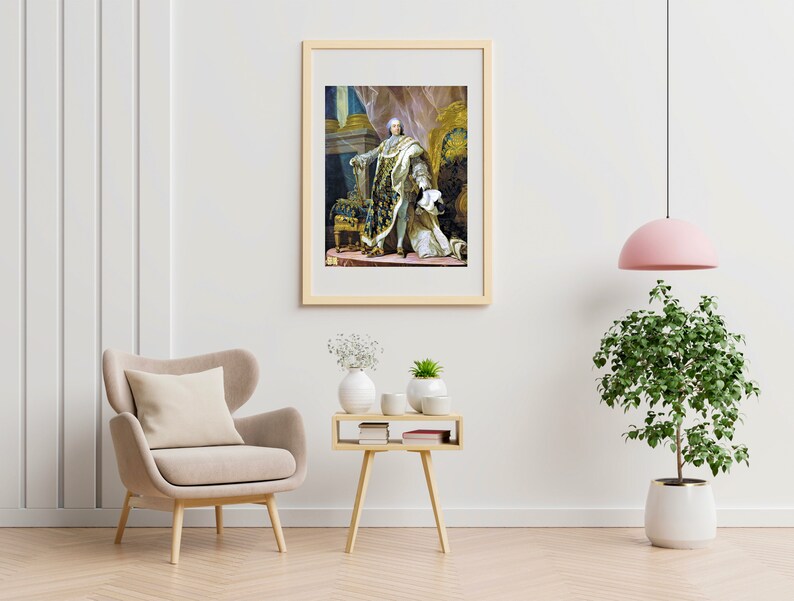 Puede incluir: Una impresi&oacute;n enmarcada de una pintura hist&oacute;rica que representa una figura con atuendo ornamentado, sentada en un trono. La obra de arte presenta colores ricos y detalles dorados, exhibida en un marco de madera clara. La habitaci&oacute;n incluye un sill&oacute;n beige, una mesita auxiliar y una planta en maceta.