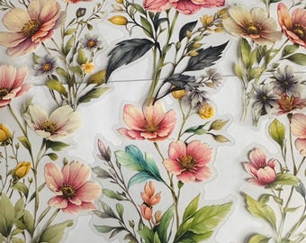 May include: Floral stickers with watercolour illustrations. The stickers depict various flowers in shades of pink, peach, yellow, and green, with detailed leaves and stems. The stickers are arranged on a white background.
