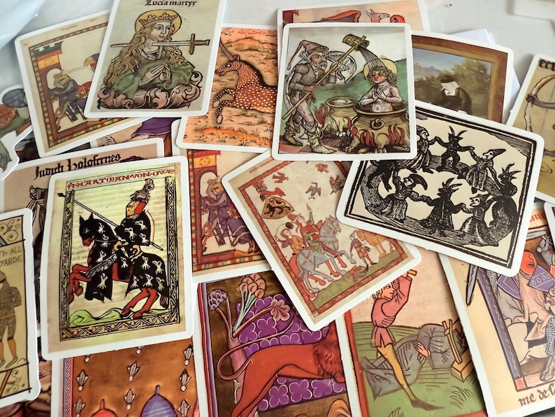 May include: A selection of vintage tarot cards with medieval illustrations. The cards depict knights, saints, and mythical creatures in various colours, including red, gold, and green. Some cards have text in a stylized font.