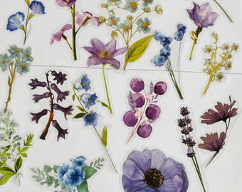 May include: A set of 12 watercolour flower stickers featuring various purple, blue, and white flowers. The stickers are perfect for adding a touch of nature to journals, planners, and other craft projects.