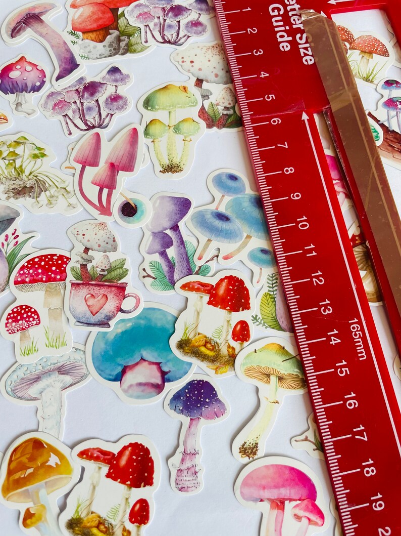 May include: A sheet of colorful mushroom stickers with watercolor designs. The stickers are various sizes and feature different types of mushrooms, including red and white toadstools, blue mushrooms, and purple mushrooms.
