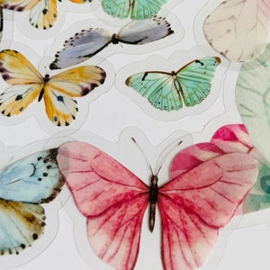 May include: A sheet of colourful butterfly stickers. The stickers feature butterflies in various colours, including pink, blue, green, and yellow. The butterflies are all different sizes and shapes.