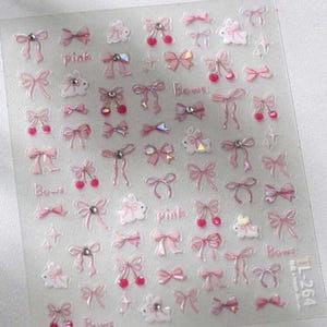 May include: A clear sheet of adhesive nail art stickers featuring various pink bows, white rabbit silhouettes, and small red cherry motifs. Some bows are accented with small clear rhinestones. The text "pink" and "Bows" appears in small font.