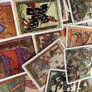 May include: A selection of vintage tarot cards with medieval illustrations. The cards depict knights, horses, and other figures in various colours, including red, green, and gold. The cards are arranged in a scattered pattern, with some text visible on the cards.