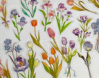 May include: A sheet of colourful floral stickers featuring various flowers, including irises, tulips, and forget-me-nots. The stickers are transparent and have a glossy finish.
