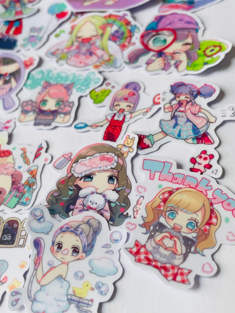 May include: A collection of colourful stickers featuring cartoon characters with different expressions and poses. The stickers are on a white background and include phrases like "Thank You" and "Welcome".