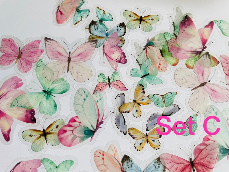 May include: A set of colourful butterfly stickers with a watercolour effect. The stickers are on a white background and feature a variety of butterfly designs, including pink, green, blue, and yellow butterflies. The text "Set C" is visible in the lower right corner of the image.
